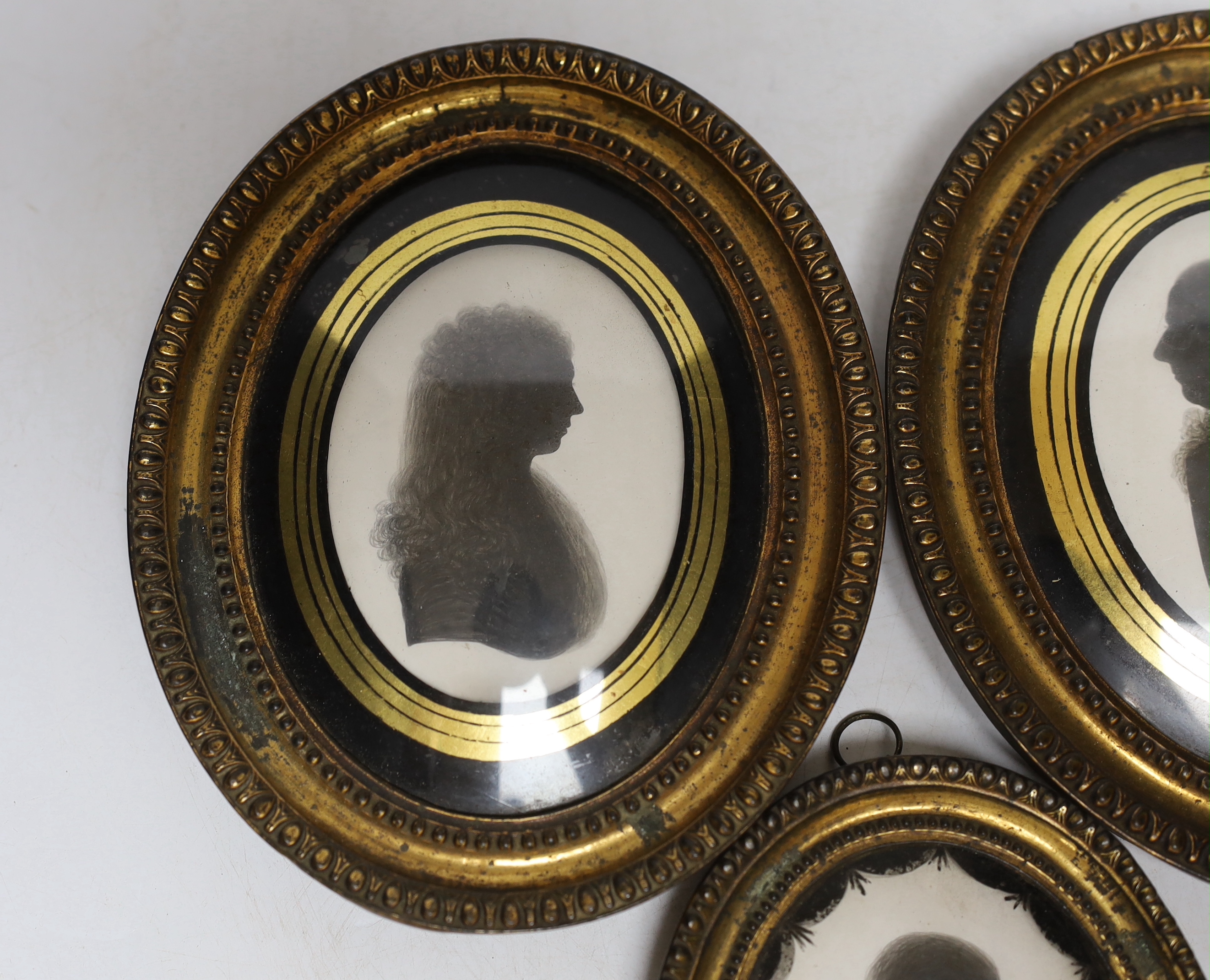 Three late Georgian silhouette portraits, verre eglomise mounts, largest 17cm high